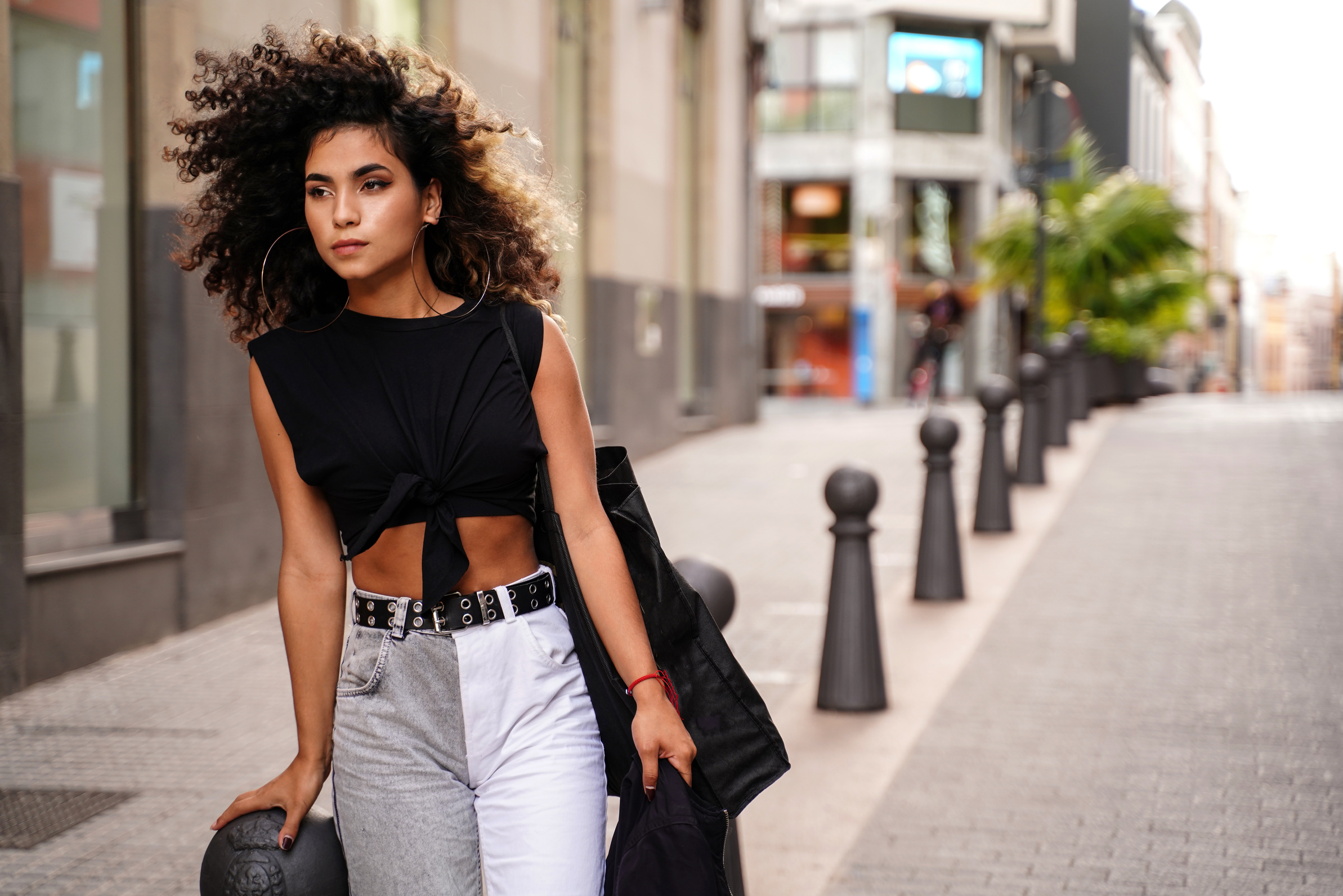 Fashionable colombian woman with afro hairstyle walking on the city street.